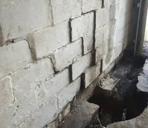Structural engineer assessing cracked foundation wall for repair cost estimate